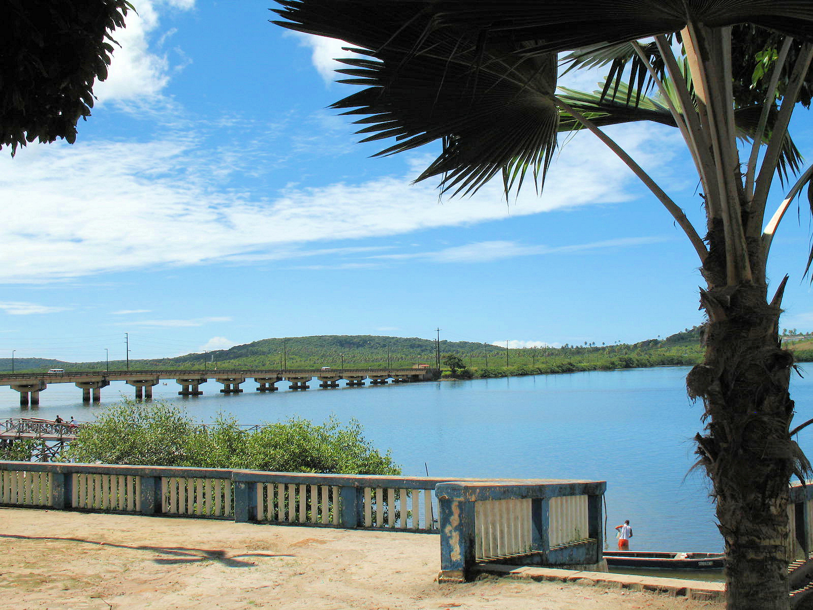 View of a bridge extending out across the water towards the lush island of Itamaraca, Brazil