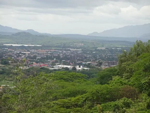 A panoramic view of Esteli. This town is surrounded by green mountains which rise up in the distance.