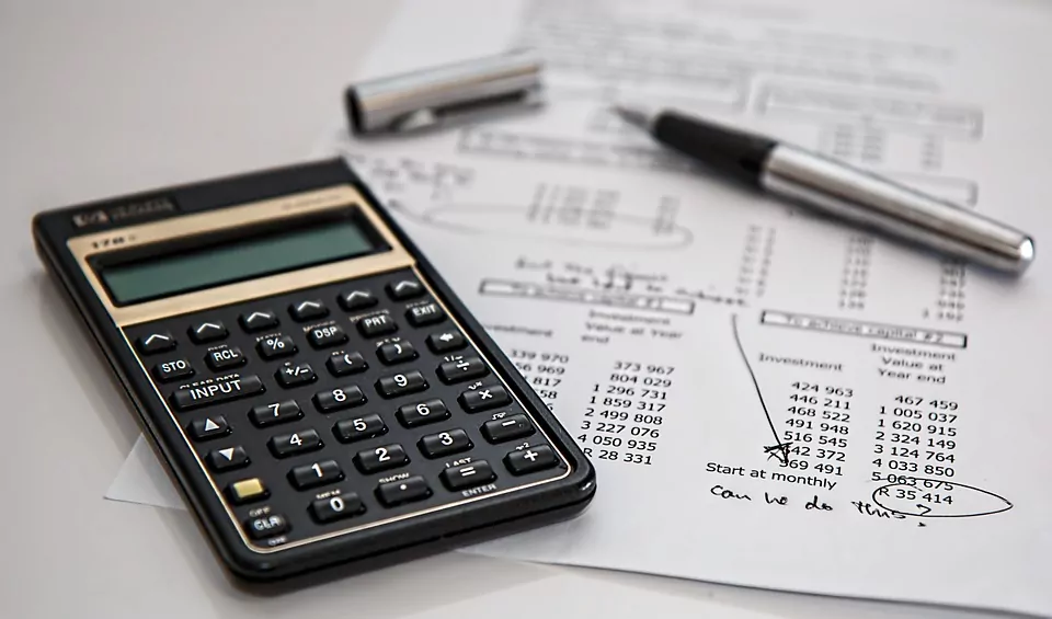 desk with calculator, pen and a sheet with monthly balances on