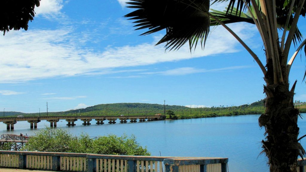 View of a bridge extending out across the water towards the lush island of Itamaraca, Brazil
