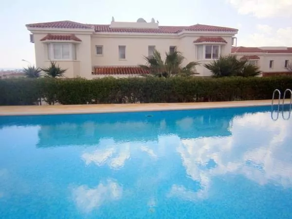 A poolside view of a villa for sale