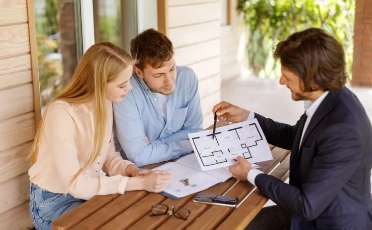 Real estate agent showing house plan to a couple at table on porch
