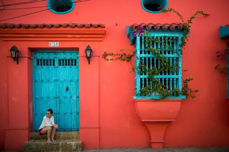 A woman sits on the steps of a house in Cartagena, Colombia.