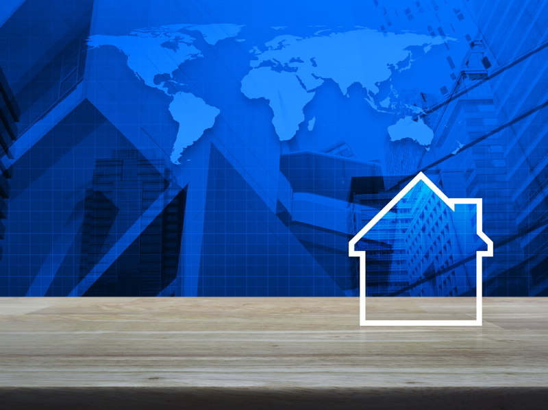 House icon on wooden table over world map.