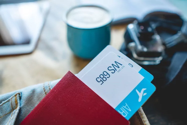 Passport and two airplane tickets sticking out of the pocket of jeans.