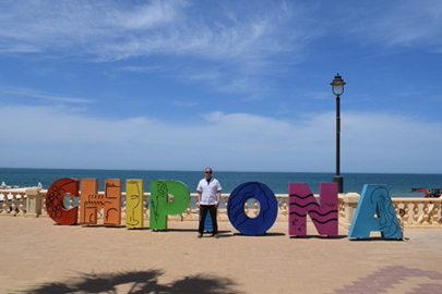 Con Murphy standing in front of a sign that says Chipiona in Spain