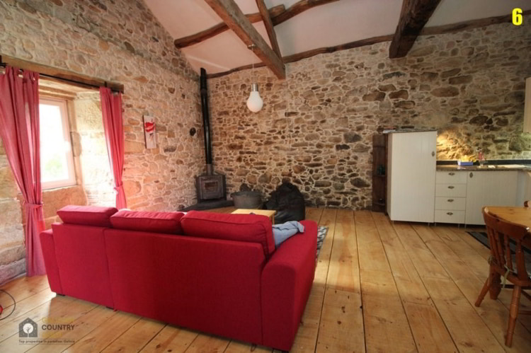 A living room with a red couch and stone walls in A white house in Xerdiz, Spain