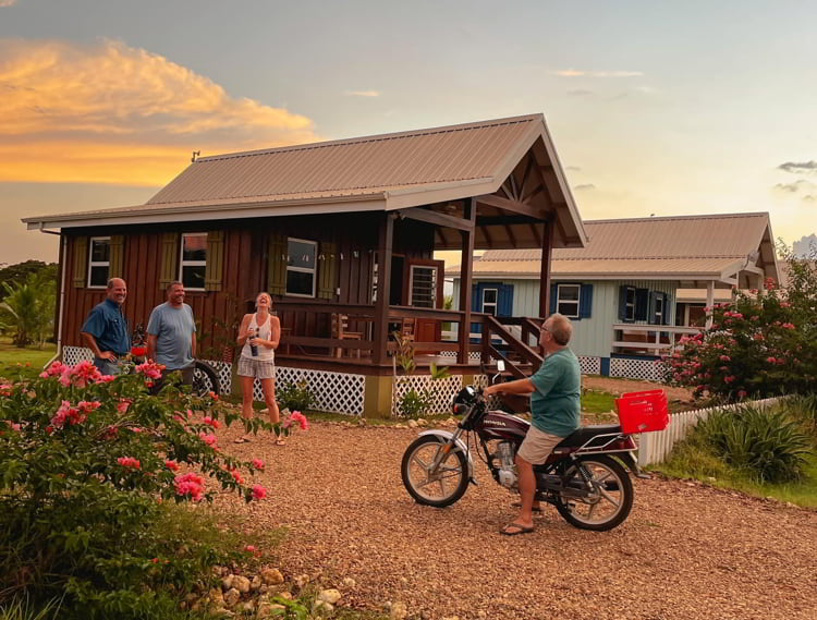 Happy residents of Carmelita Gardens, Belize in front of a house during sunset