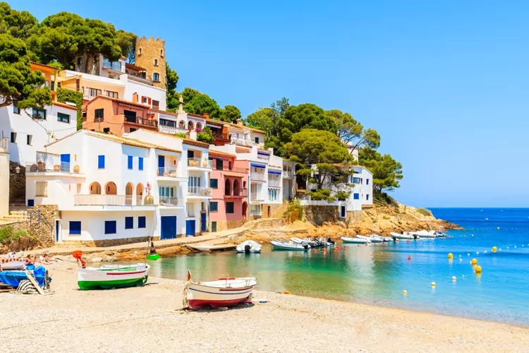 Fishing boats on beach in Sa Tuna village with colorful houses on shore, Costa Brava, Catalonia, Spain, a booming property market