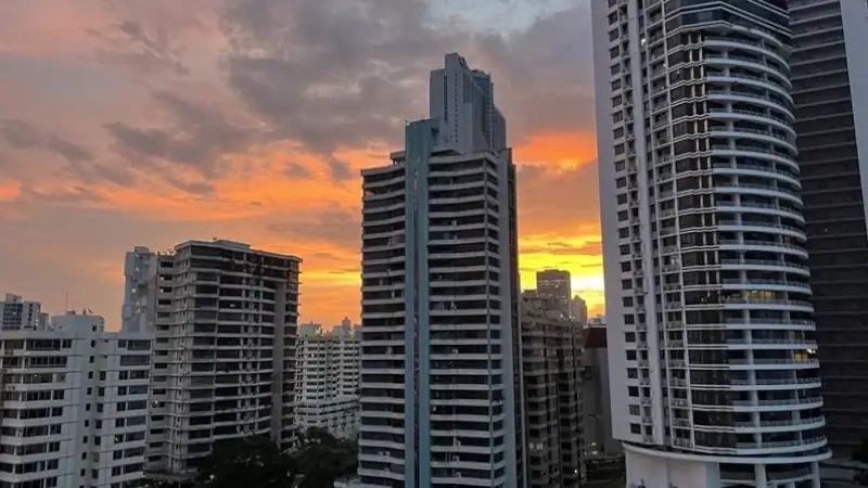 Sunrise over Panama City skyline, featuring modern high-rise buildings against a dramatic orange and purple sky. Ideal for travel, architecture, or urban lifestyle content.