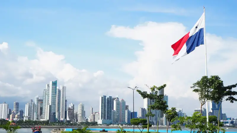 City skyline with green grass and flag flying. Blue sky and white clouds.