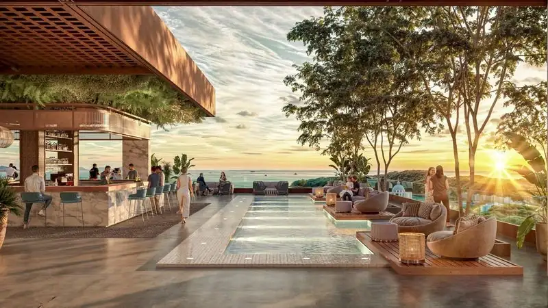 Luxury condominium rooftop terrace featuring a swimming pool, elegant lounge seating, and a bar with panoramic sunset views surrounded by lush greenery.