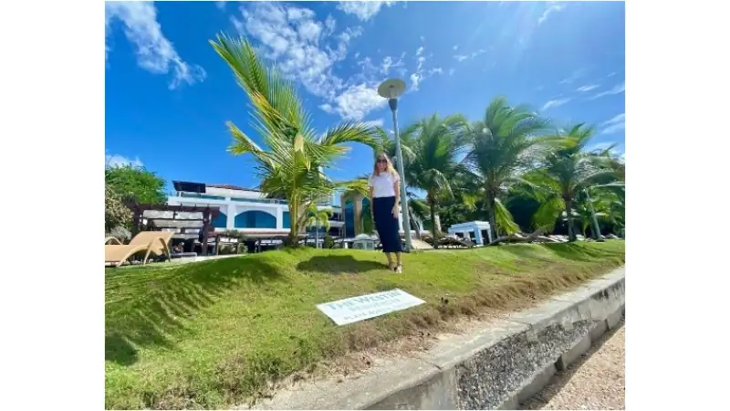Sophia stands on a sunny hotel lawn surrounded by lush palm trees, outdoor seating, and a modern building beneath a bright blue sky in Panama City, Panama.