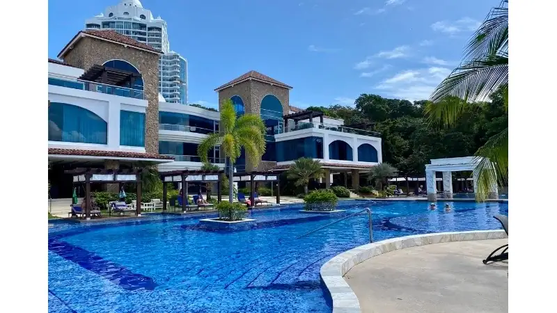A luxurious outdoor swimming pool at The Westin Playa Bonita in Panama, featuring turquoise waters, elegant modern architecture, tropical palm trees, and a clear blue sky.