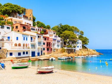 Fishing boats on beach in Sa Tuna village with colorful houses on shore, Costa Brava, Catalonia, Spain, a booming property market